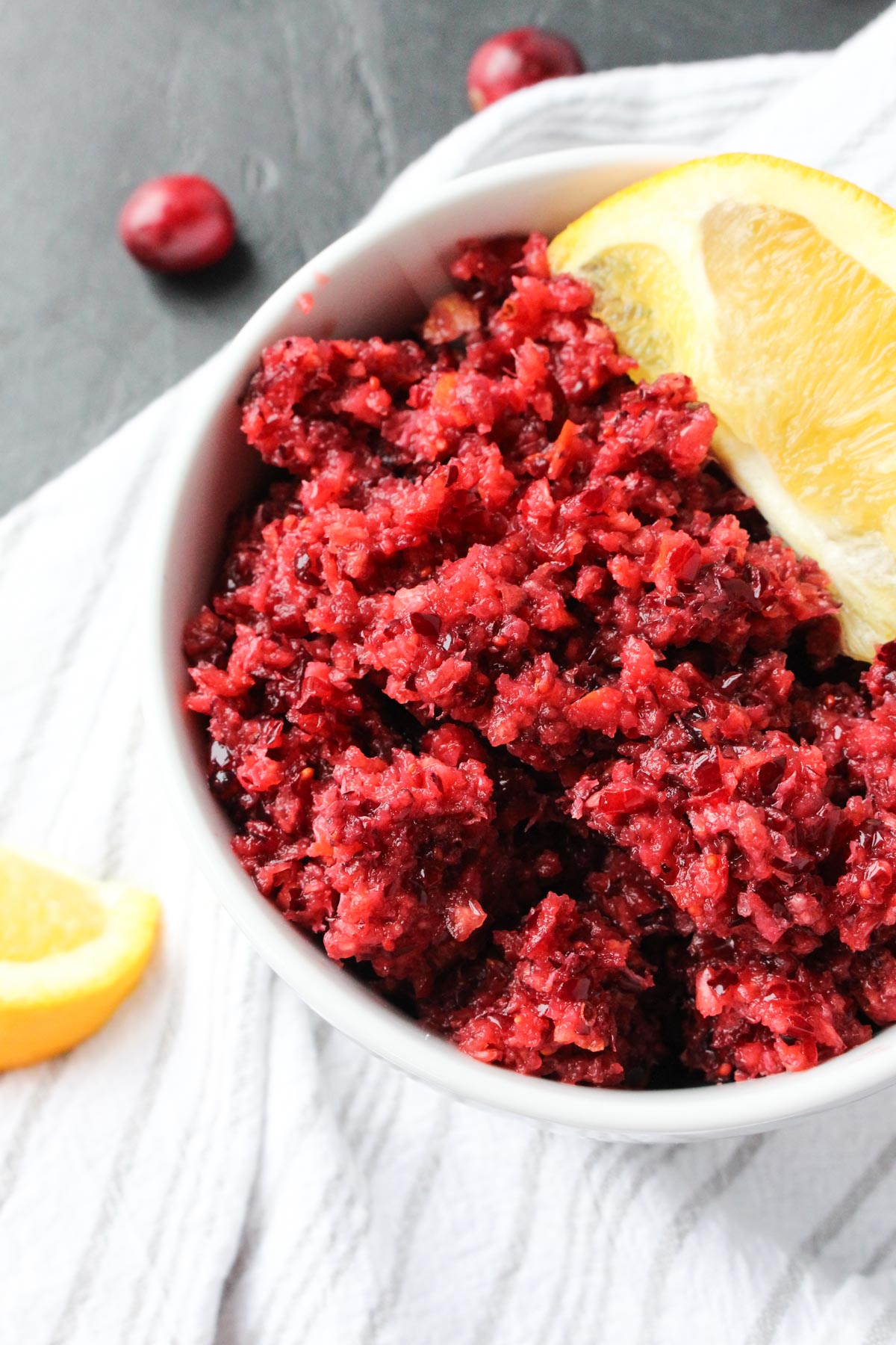 Easy cranberry relish with vibrant red color and a juicy orange peel on the side.