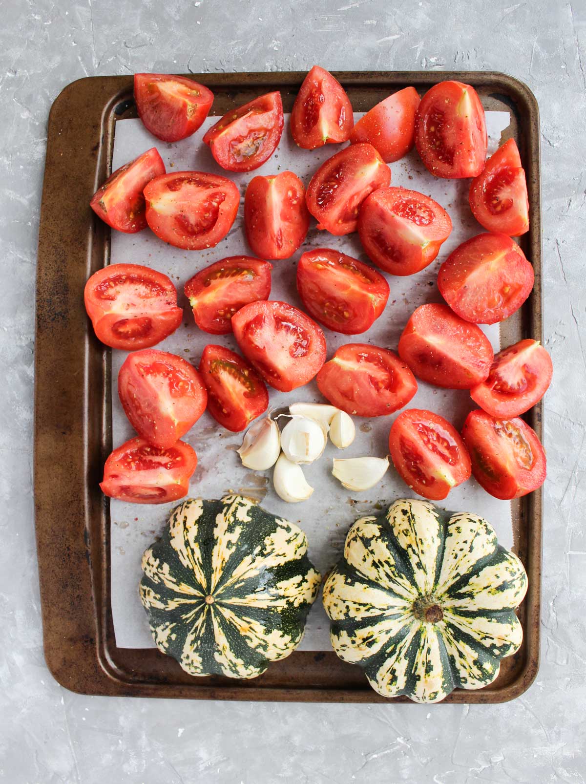 Baking sheet with tomatoes, garlic, and squash.