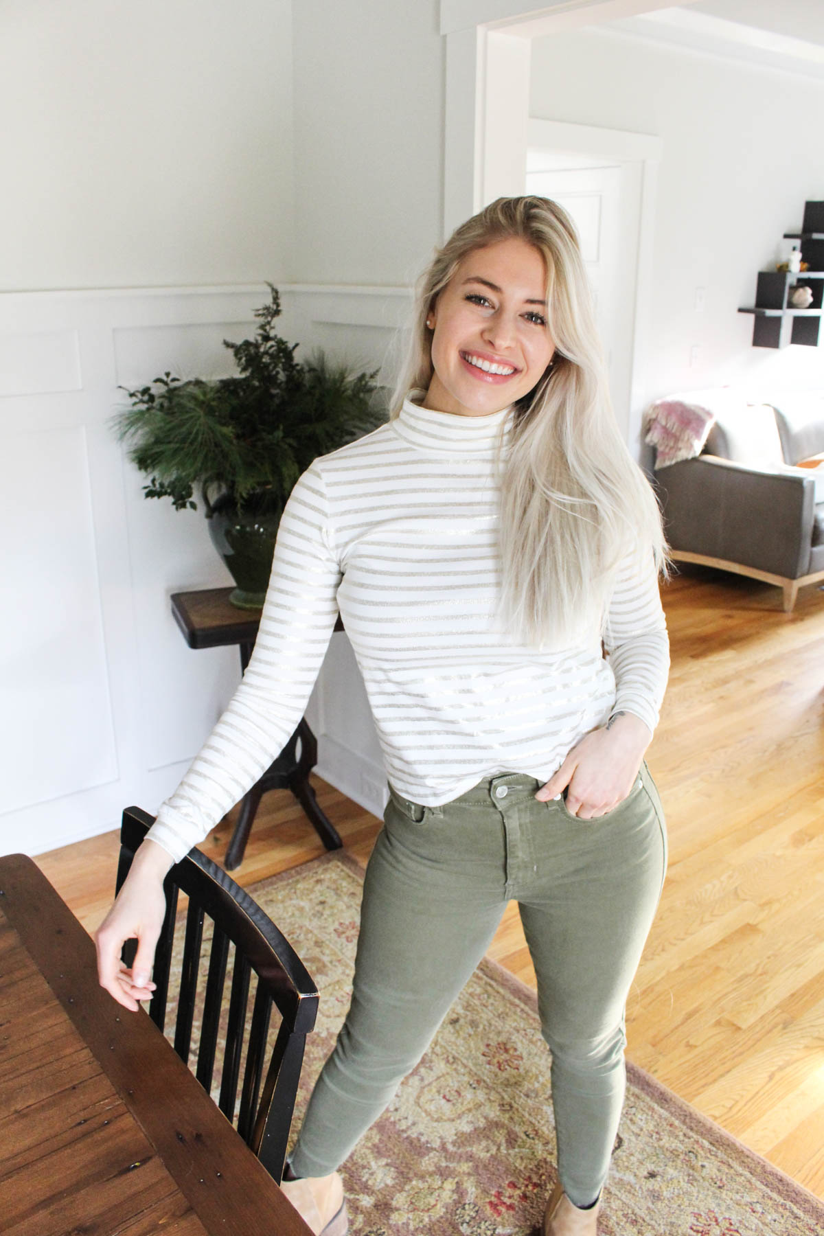 Girl in white shirt and green pants standing.