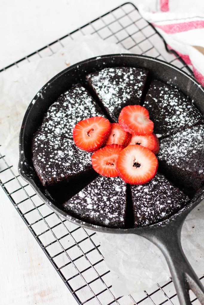 Overhead shot of cake slices in the skillet with powdered sugar and strawberries on top.