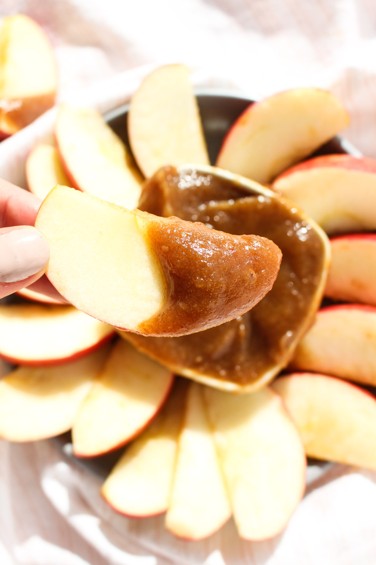 Hand holding slice of apple with dip.