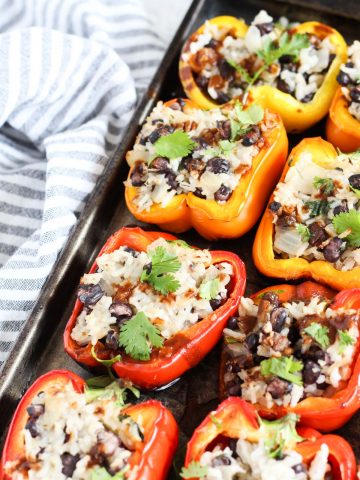 Grilled stuffed peppers lined up on a baking sheet.