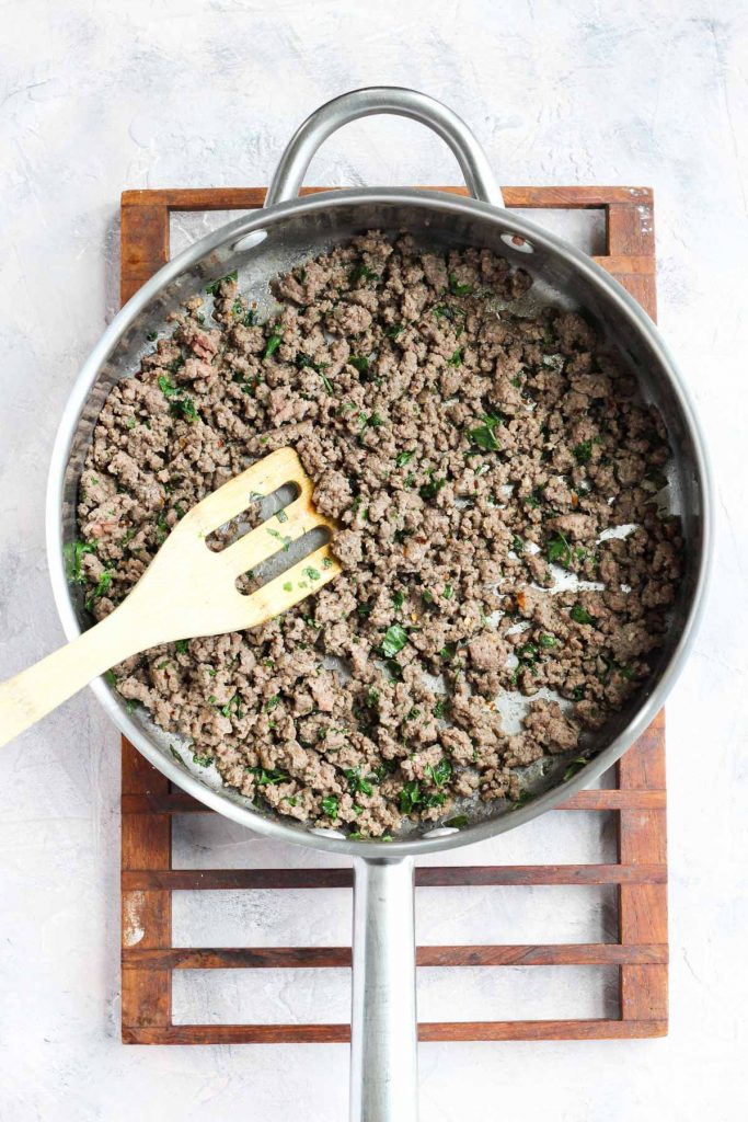 Ground beef and herbs cooked in pan.