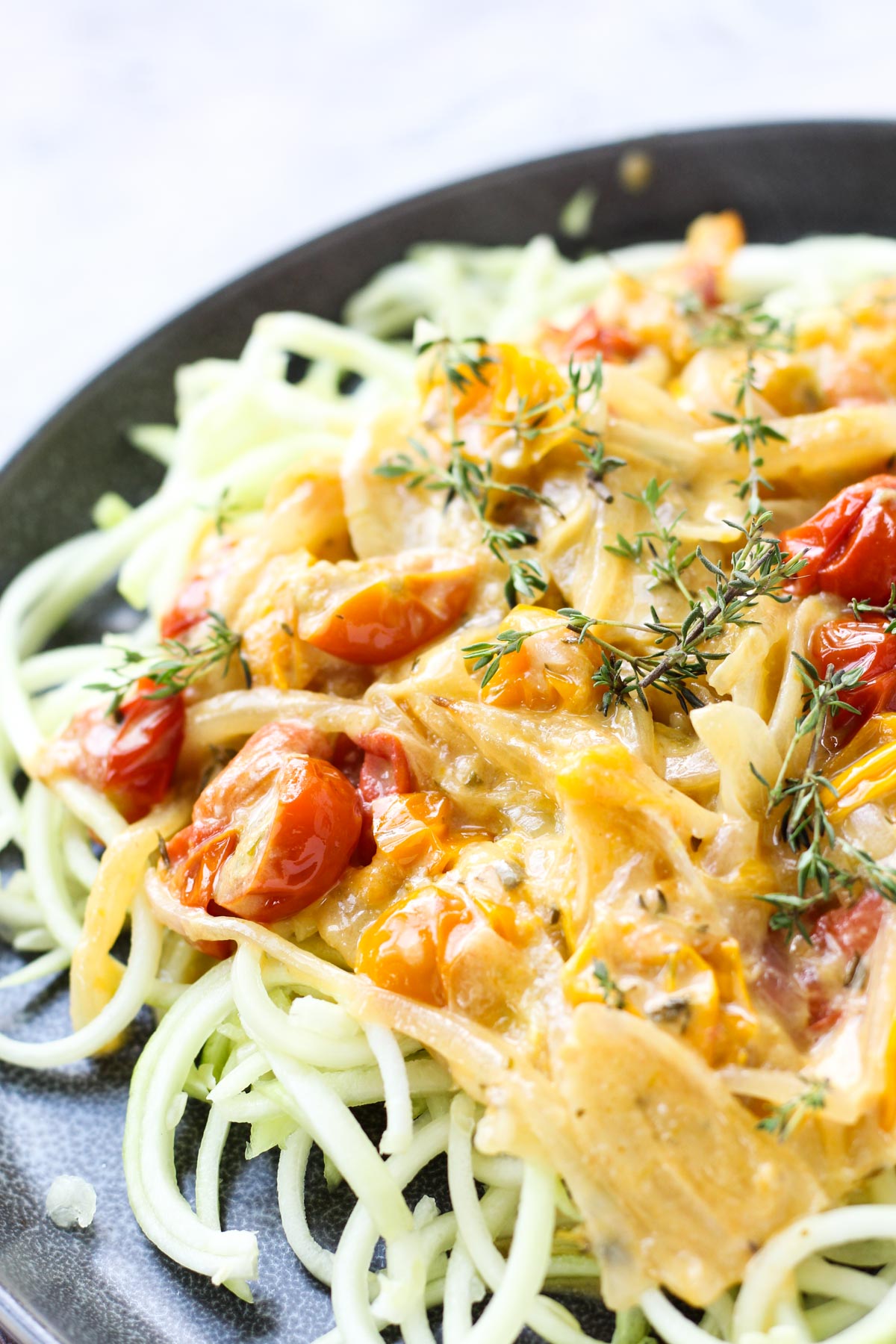 Plate of zucchini noodles with creamy cherry tomato sauce on top.