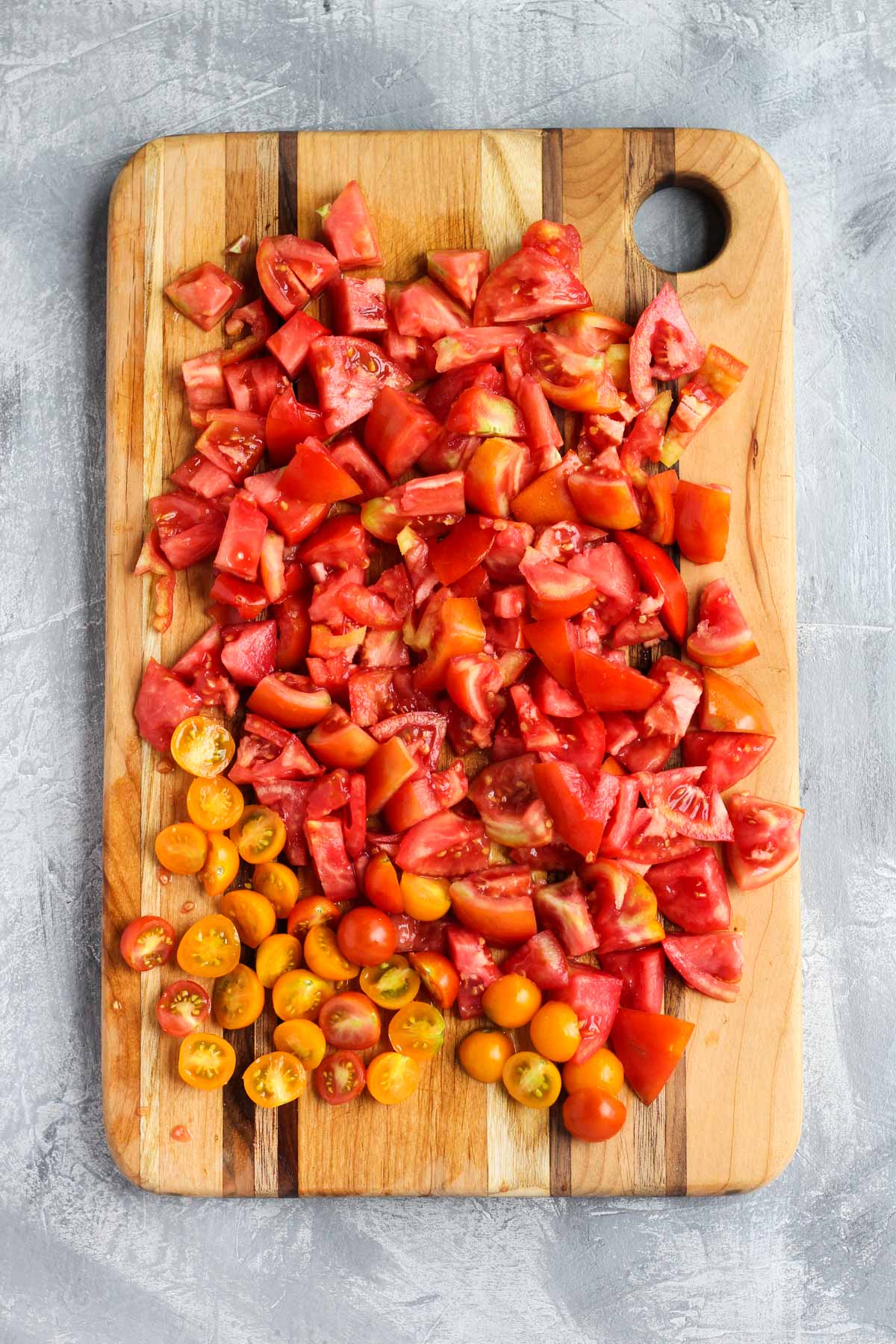 Tomatoes chopped on wooden cutting board.