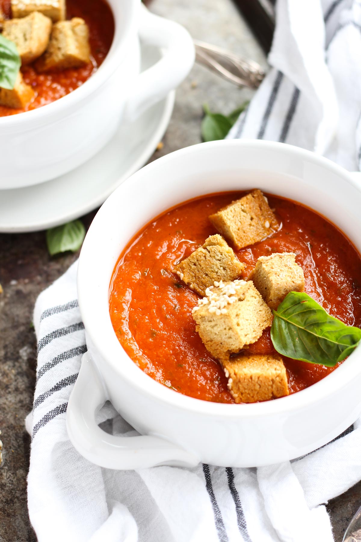 Tomato basil soup in a white bowl with croutons.