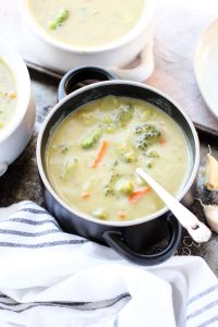 Bowl of creamy broccoli soup with a spoon leaning on the side.