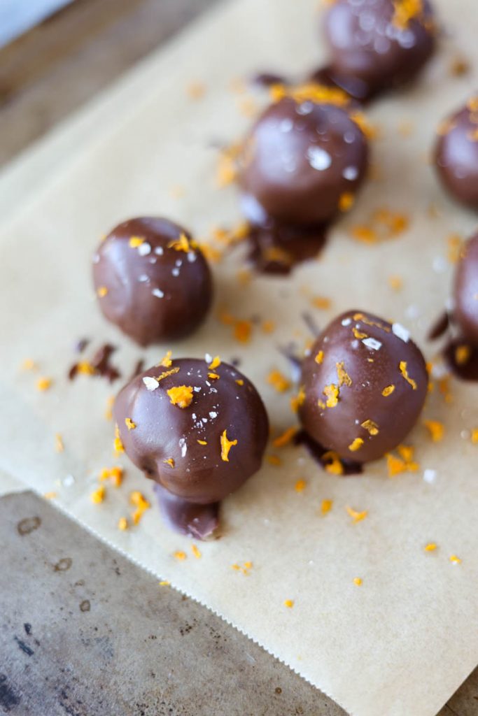 Truffles dipped in chocolate with orange zest on top.