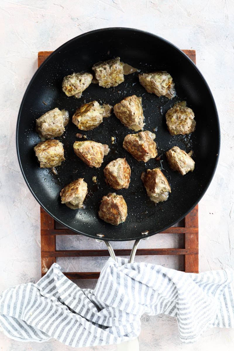 Cooked meatballs in frying pan.