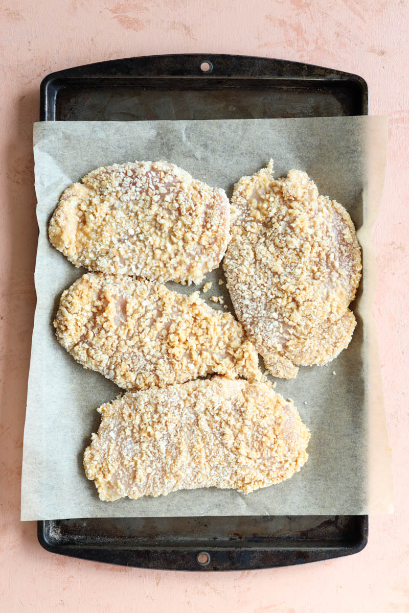 Crispy chicken on a parchment paper lined baking sheet.