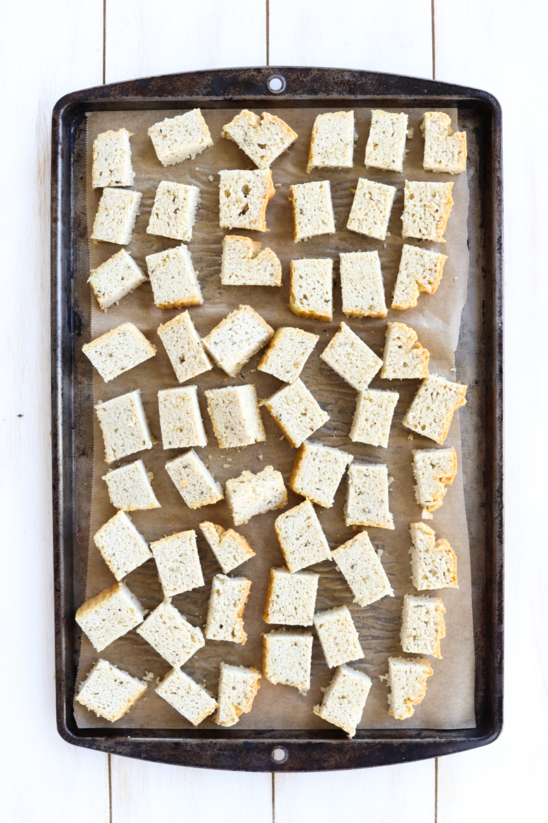 gluten free bread cut into cubes on a parchment paper lined baking sheet.