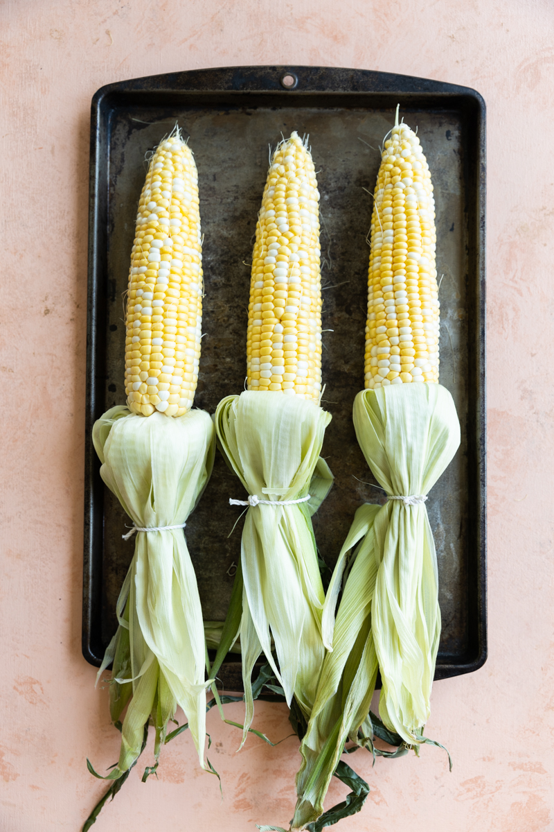 Corn on the cob with the husk pulled back and tied.