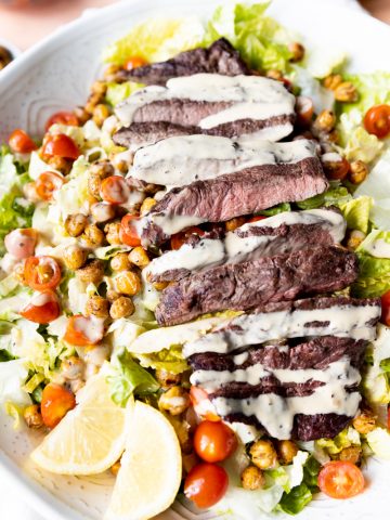 Steak Salad with caesar dressing drizzled on top.