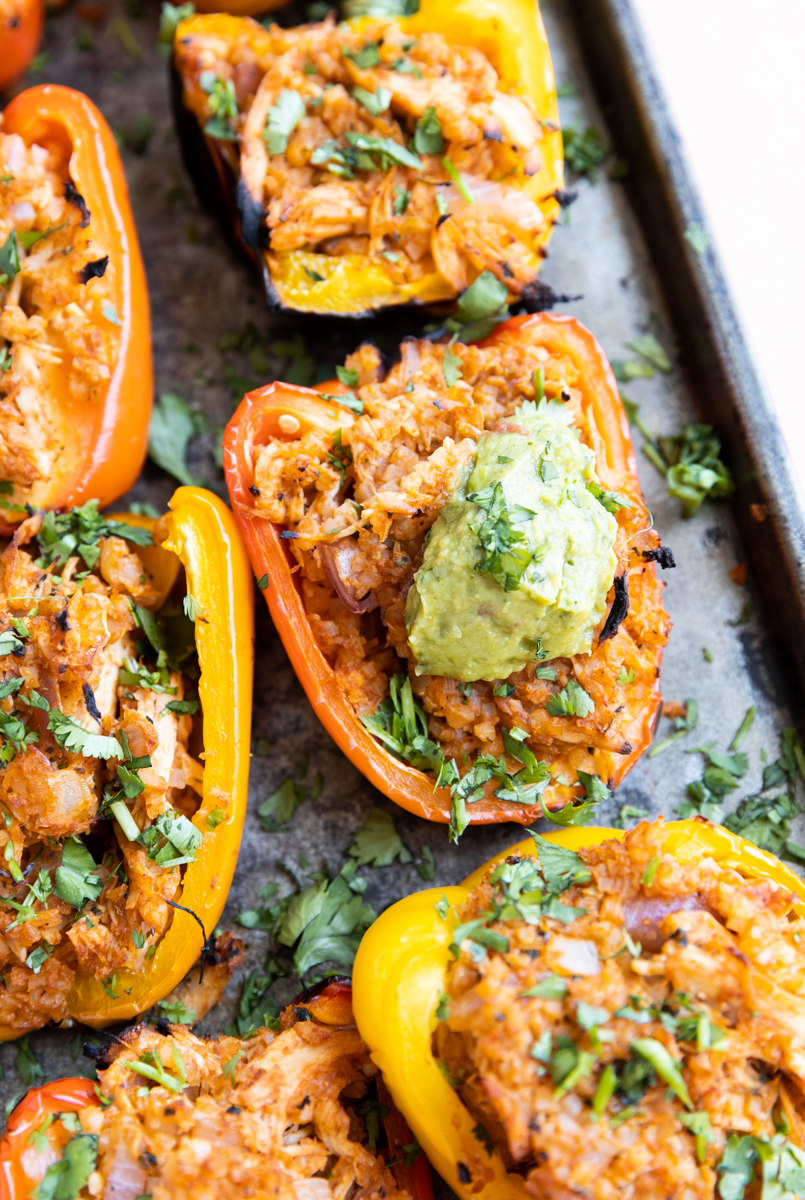 Close up of bbq chicken stuffed peppers with guacamole on top.