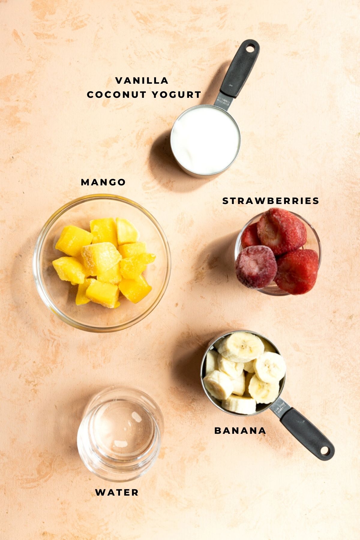 Ingredients for mango strawberry banana smoothie measured out into small cups.