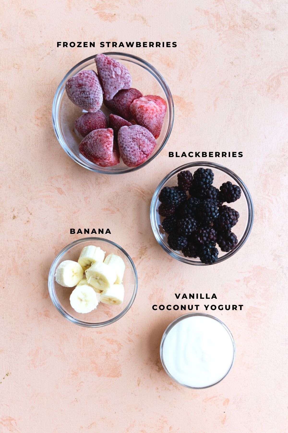 Strawberries, blackberries, bananas, and coconut yogurt in bowls.