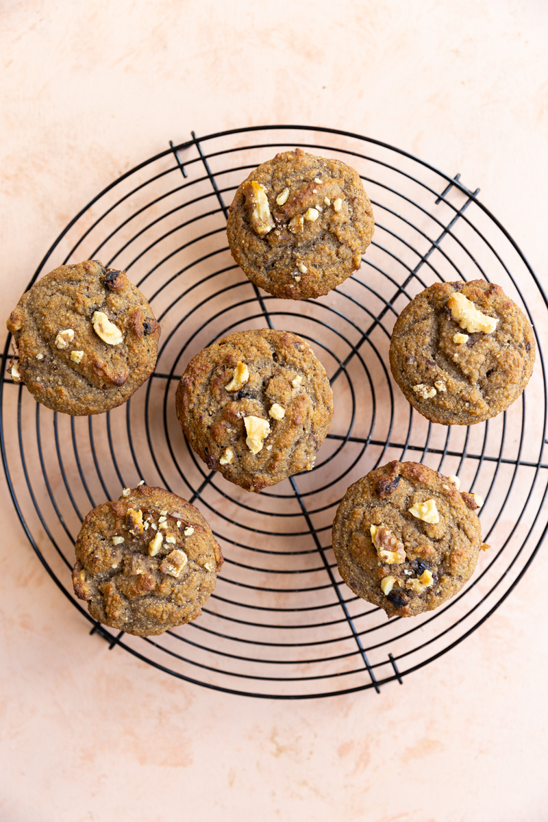 Golden brown cranberry walnut muffins on a metal cooling rack.