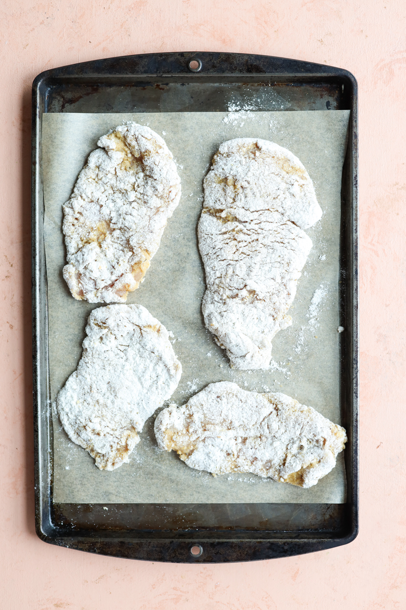 Breaded chicken cutlets on a baking sheet.