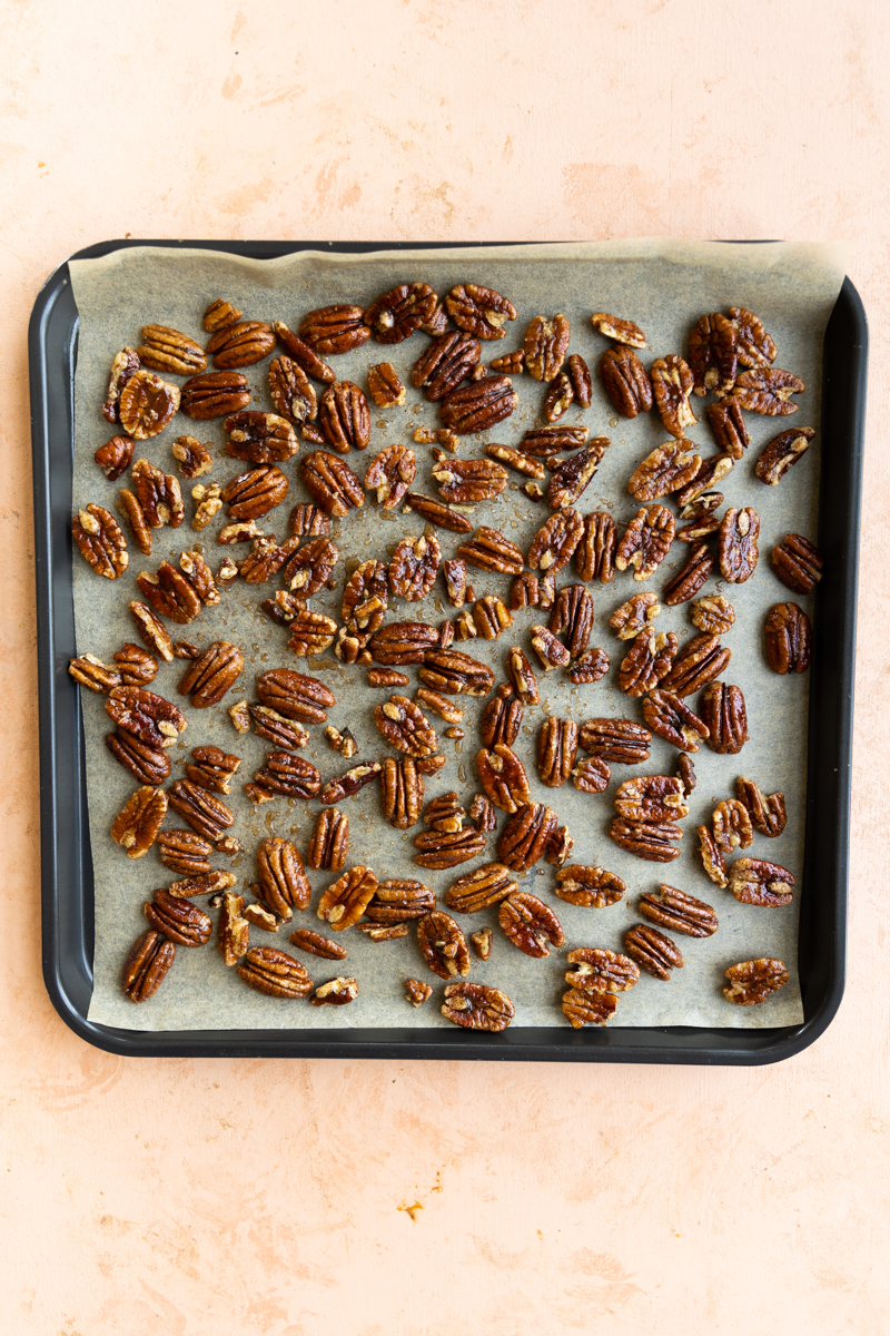 Candied pecans on parchment paper lined baking sheet.