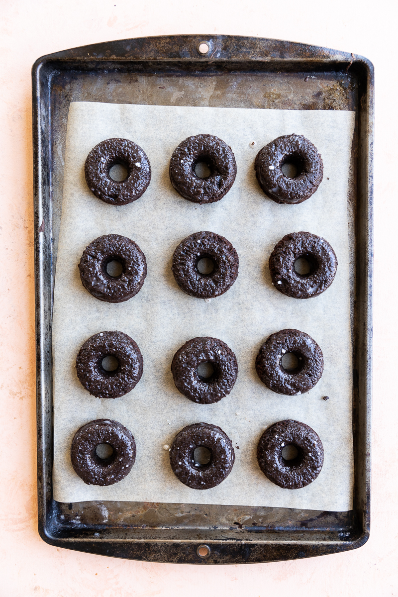 Glazed chocolate mini donuts on parchment paper.
