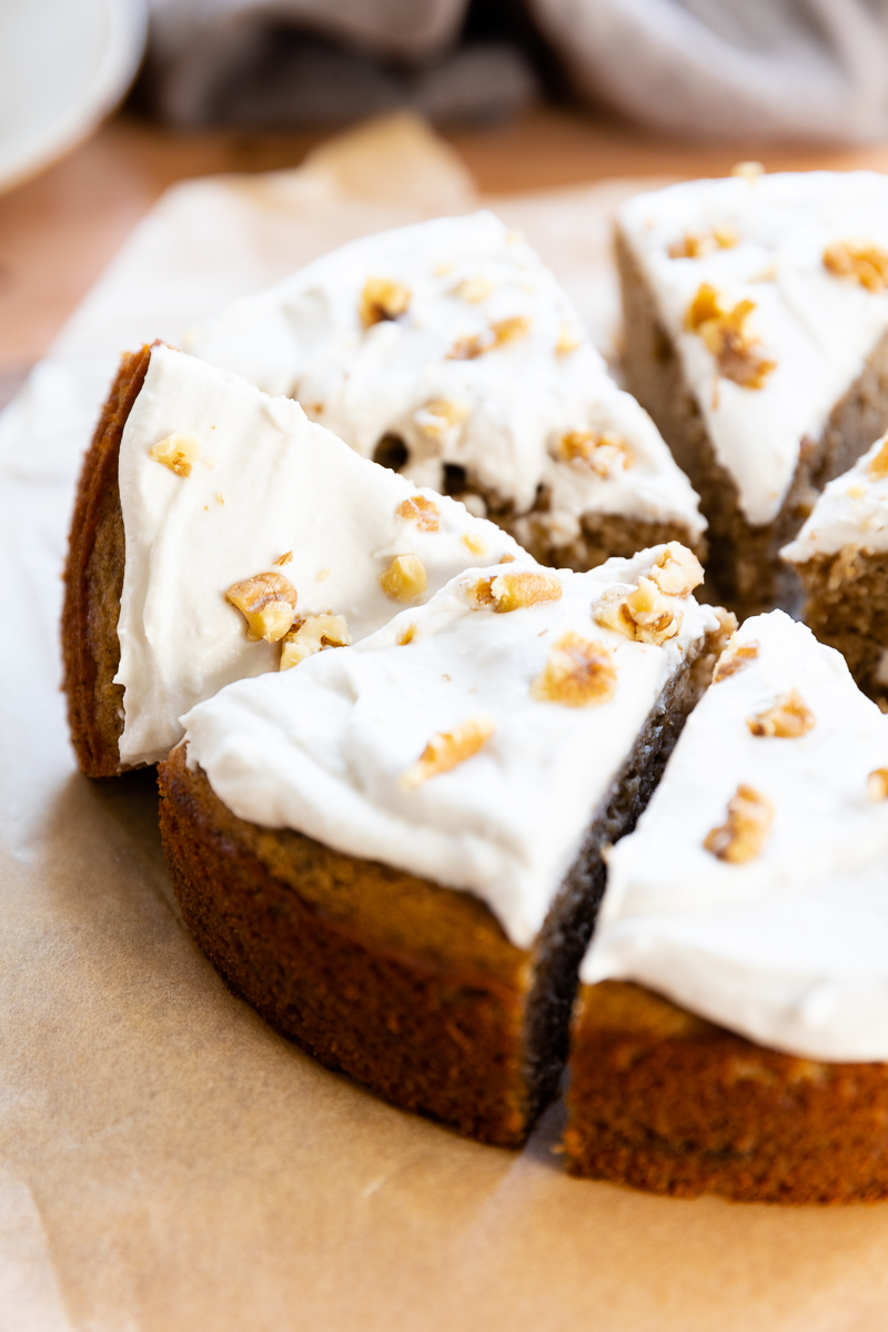 Banana cake cut into slices with walnuts and cream on top.