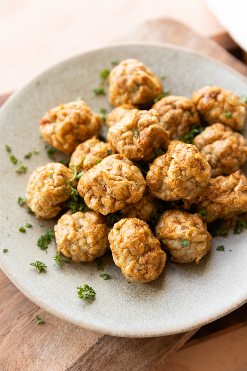 Chicken meatballs on a plate with chopped parsley.