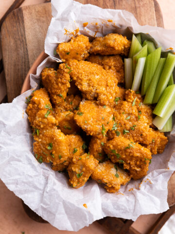 Baked spicy chicken nuggets in basket with celery.