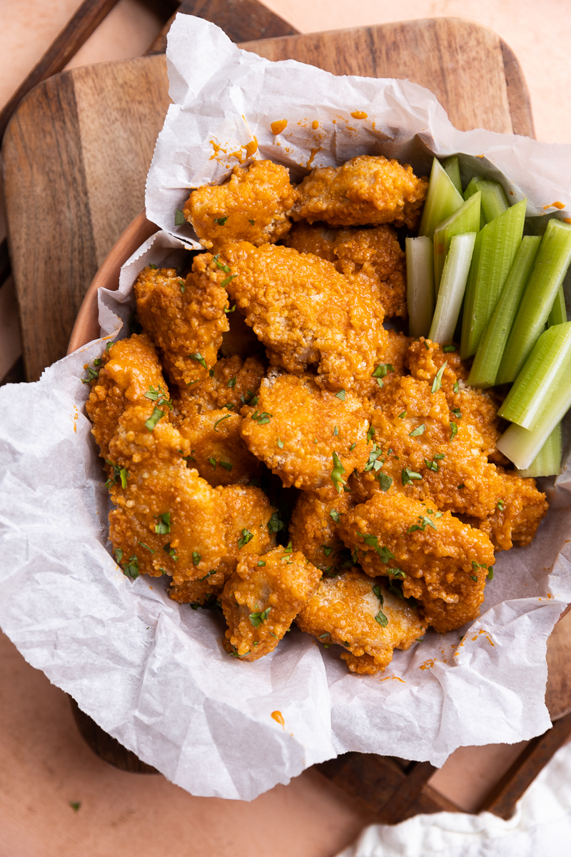 Baked spicy chicken nuggets in basket with celery.