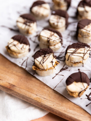 Frozen banana bites with dark chocolate drizzled on top.