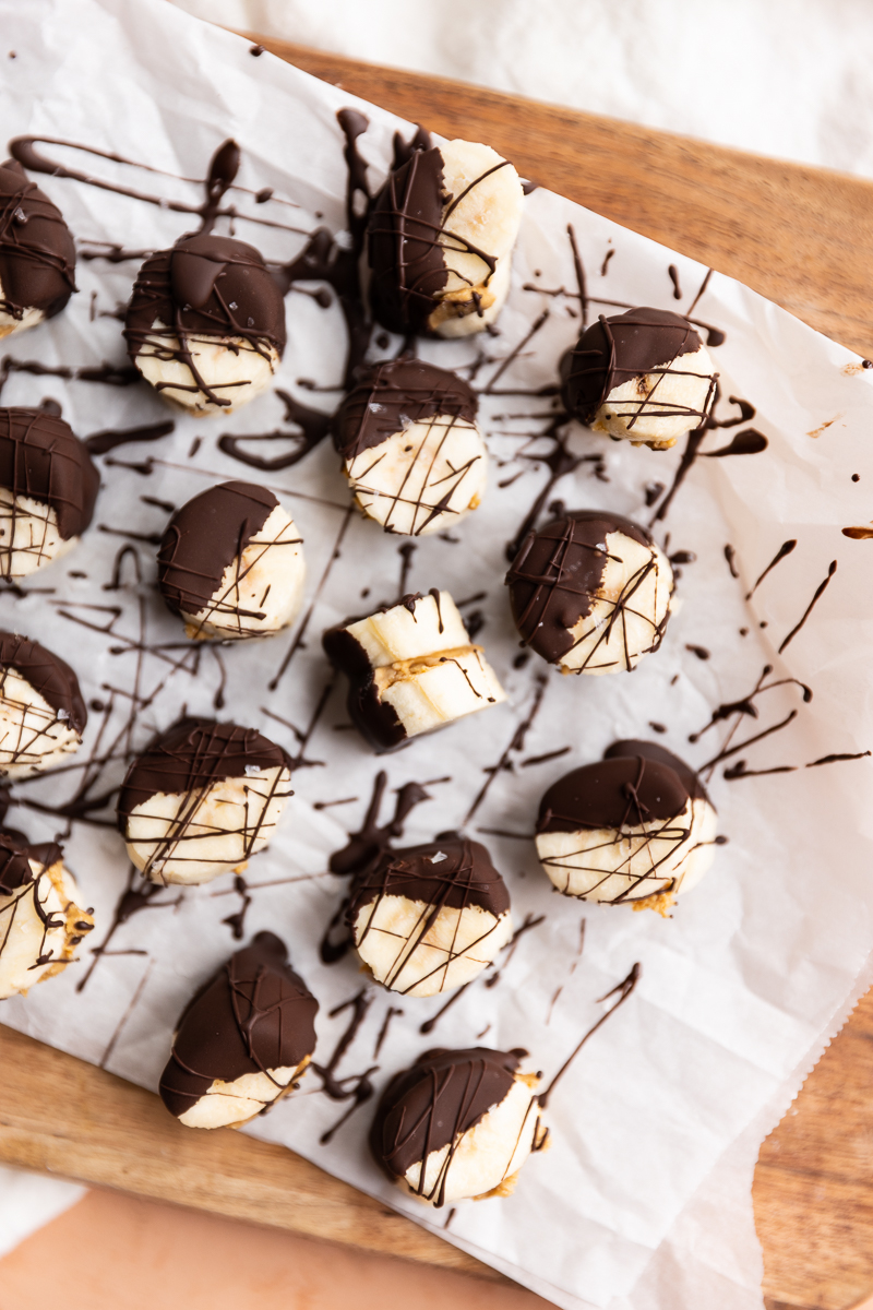 Banana bites dipped in chocolate on parchment paper.