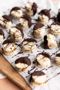 Frozen banana bites on a parchment paper lined board.
