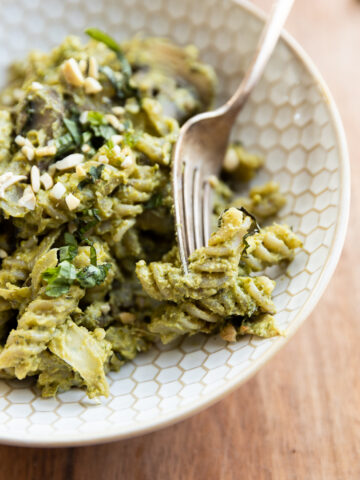 Fork scooping out pesto pasta.