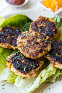 Spicy chicken burgers on a plate of romaine lettuce.