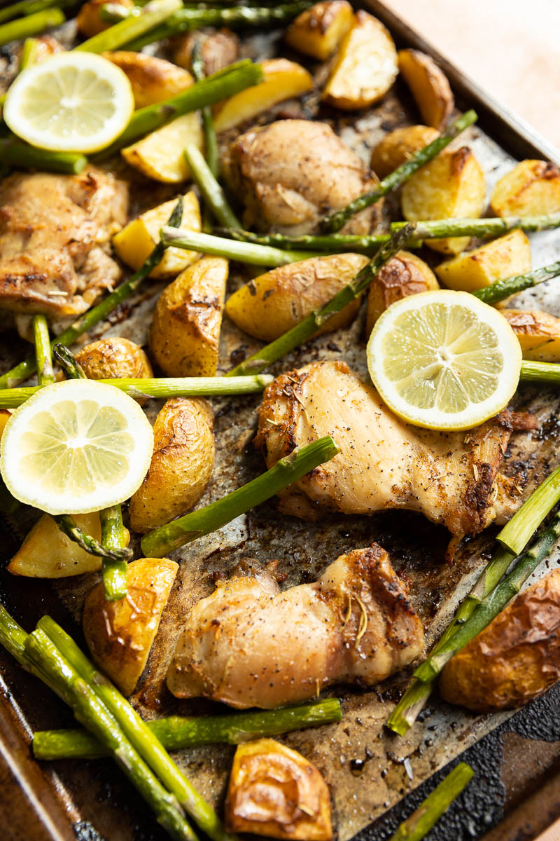 Lemon chicken on a tray with asparagus and potatoes.