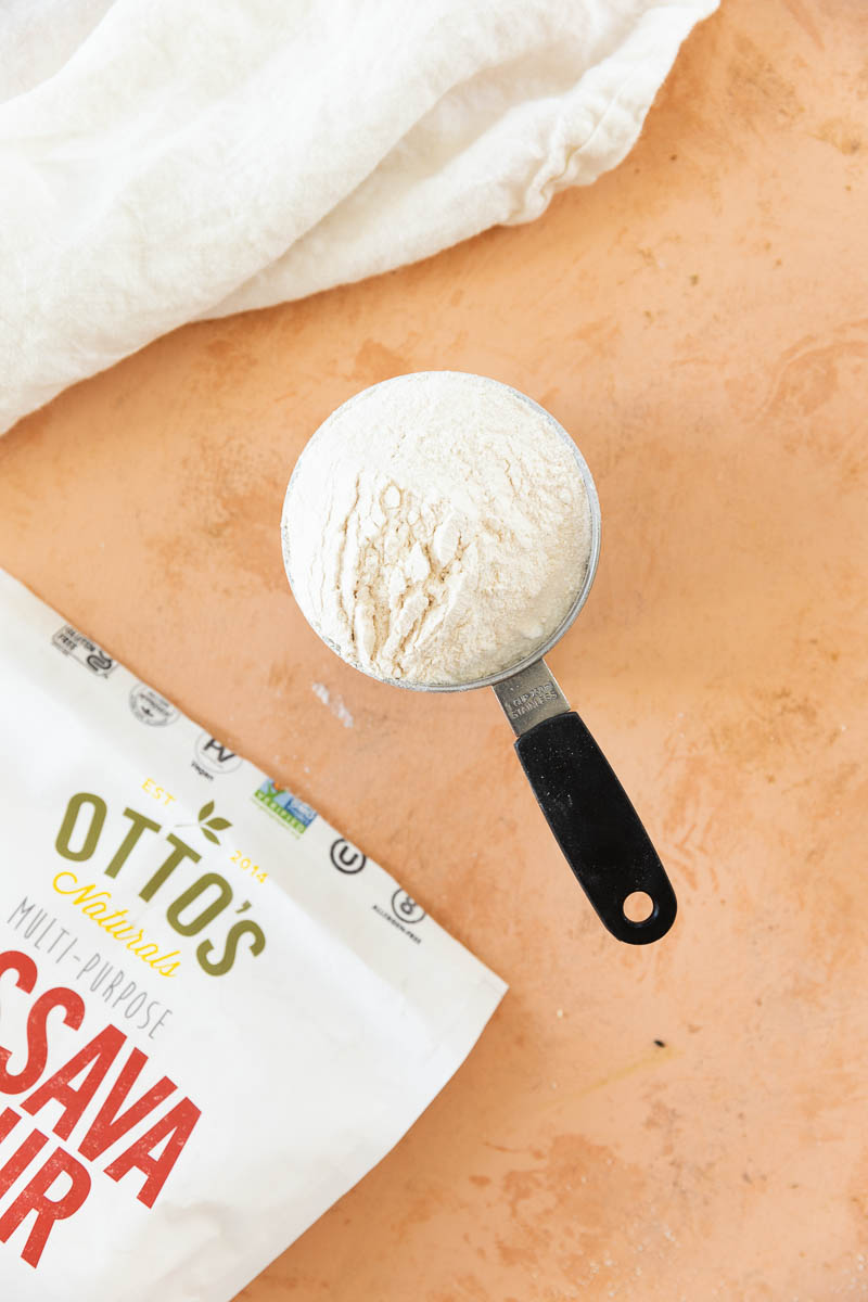 Cassava flour in a measuring cup with a bag next to it.