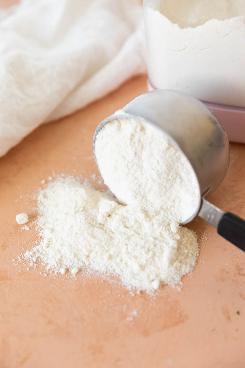 Measuring cup tipped on its side spilling out coconut flour.