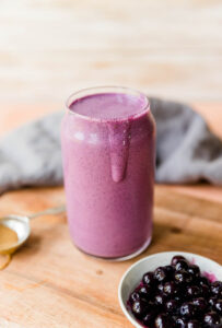 Blueberry protein shake with smoothie dripping down the side.
