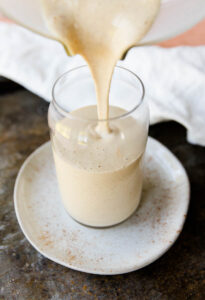 Cinnamon roll protein smoothie being poured into cup.