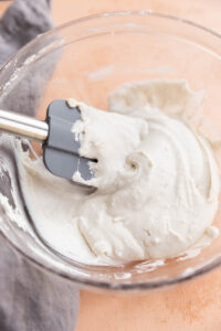 Spatula in bowl with creamy coconut whipped cream.