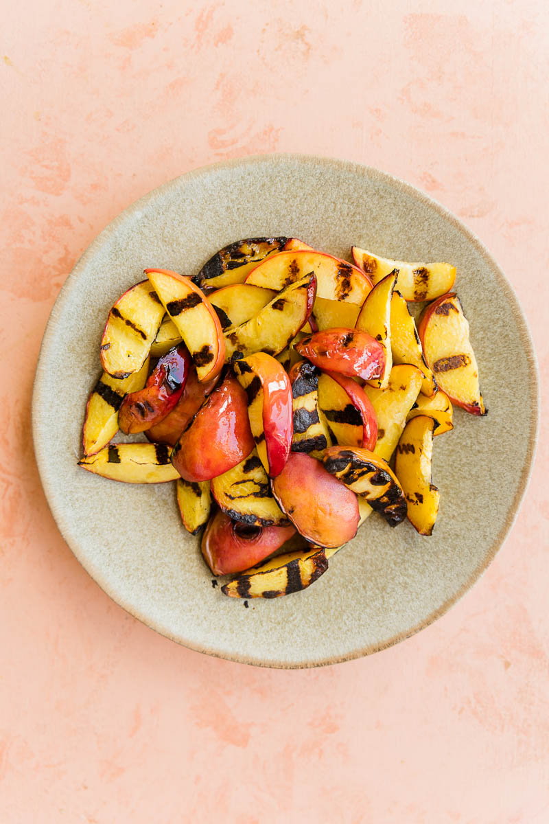 Grilled peaches on a ceramic plate.