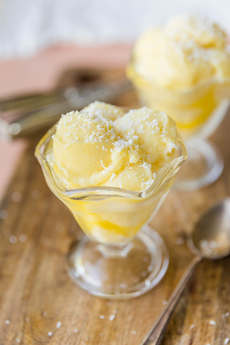 Clear glass cup with scoops of pineapple sorbet.