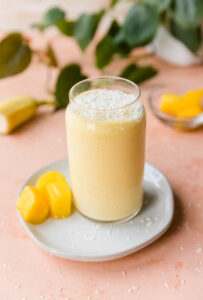 Mango protein shake on a plate with mango chunks on the side.