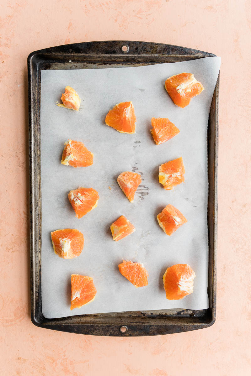 Orange chunks on a parchment paper lined baking sheet.