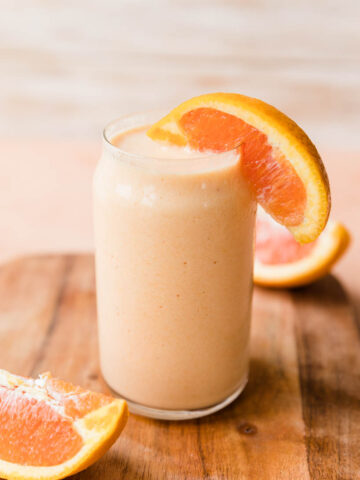 Orange smoothie with a slice of orange on the glass.