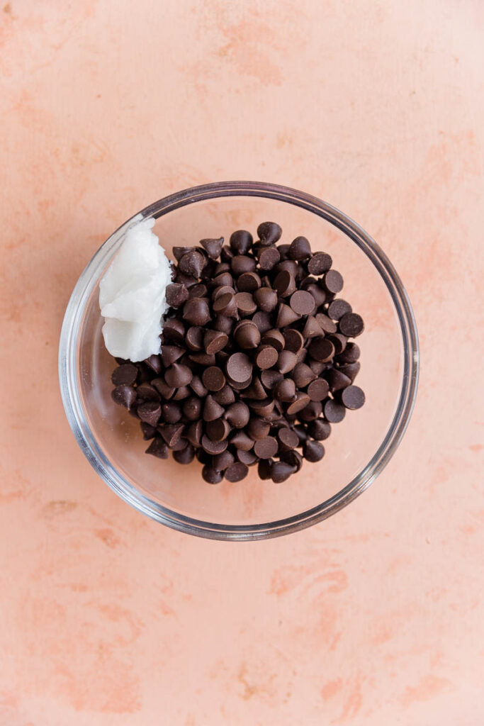 Chocolate chips and coconut oil in glass bowl.