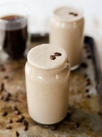 Coffee milkshake in a glass cup with coffee beans on top.