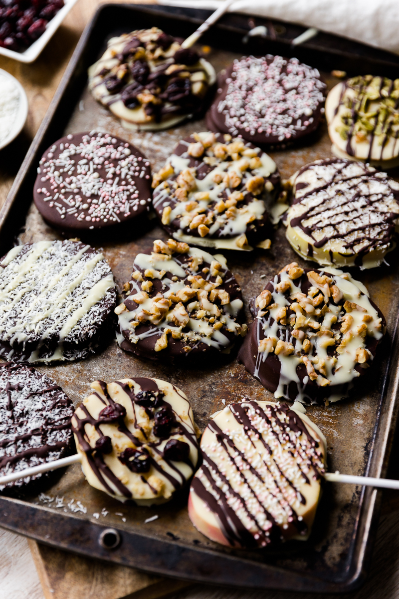 Chocolate covered apple pops lined up on a baking sheet.