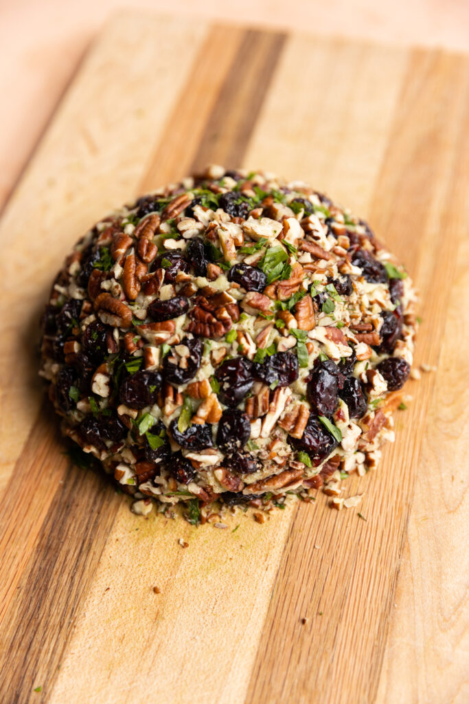 Cheese ball covered in chopped pecans and dried cranberries.