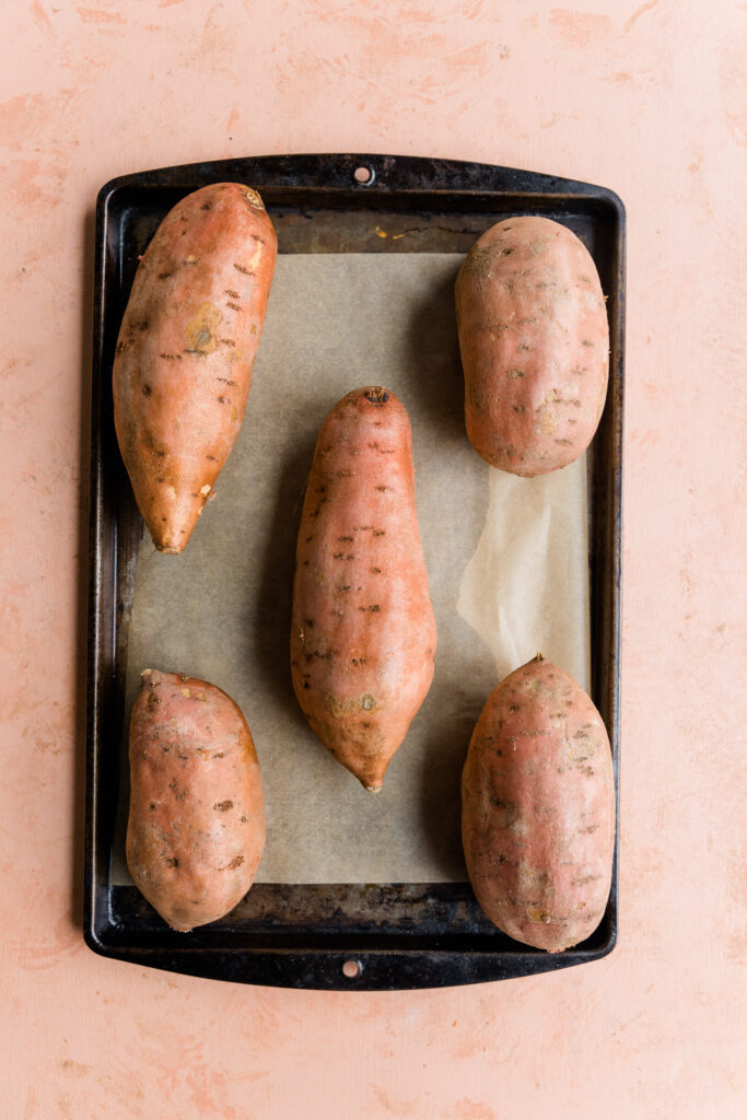 Sweet potatoes on a parchment paper lined baking sheet.