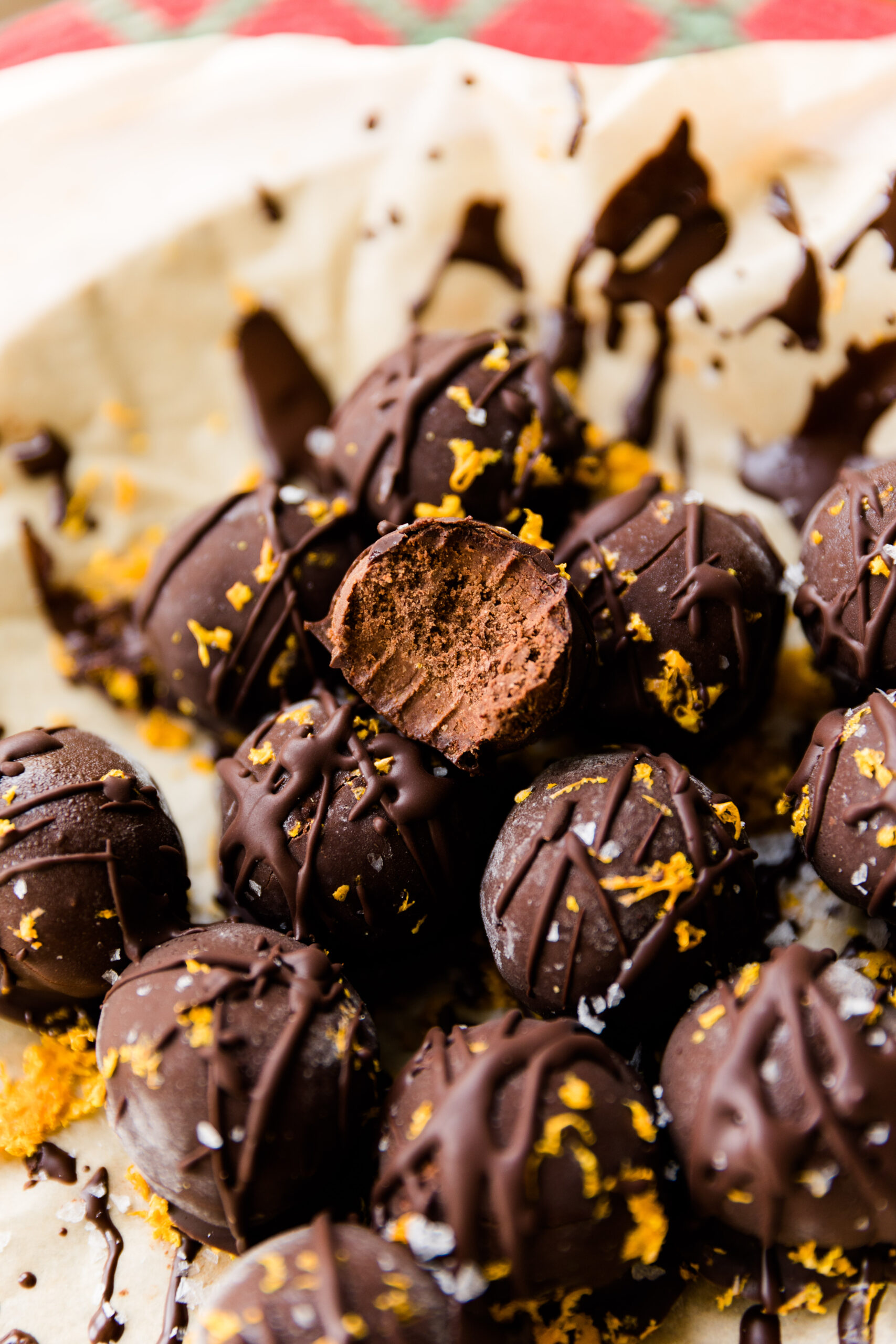 Chocolate orange truffles with a bite taken out of the one placed on top.